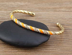 Detail of 18k gold plated bangle with orange enamel stripes and sparkling cubic zirconia