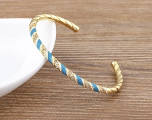Detail of 18k gold plated bangle with blue and white enamel stripes and zircons