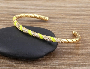 Detailed macro view of 18k gold plated cuff bracelet with enamel and zircon inlay