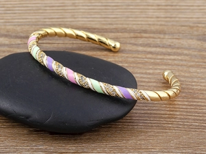 Detail of twisted 18k gold plated bangle with colorful enamel and pavé crystals