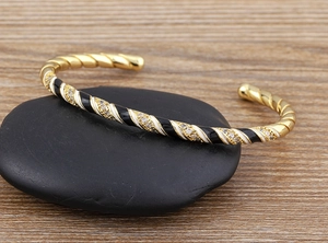 Detail of twisted 18k gold plated cuff with black and white enamel and zircon stones