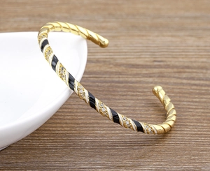 Detail of 18k gold plated open cuff with black and white enamel and zircon accents