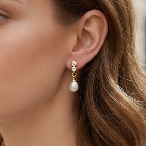 Close-up of elegant 18K gold plated drop earrings with white pearls and sparkling zircons