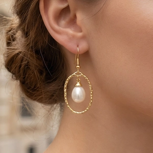 Detail of 18K gold-plated oval drop earrings with white freshwater pearl on model