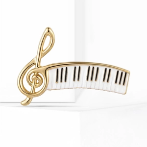 Detail of elegant gold treble clef and piano keys brooch with smooth enamel finish