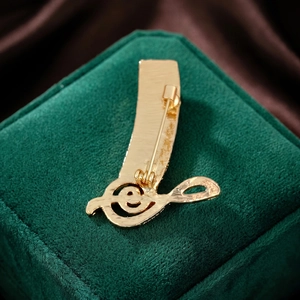 Elegant gold musical note brooch with matte finish on green velvet jewelry box