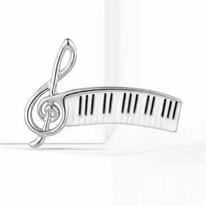 Detailed close-up of a silver treble clef brooch with elegant piano keyboard enamel pattern