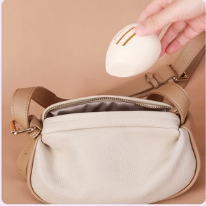 Portable white teardrop egg-shaped silicone makeup sponge case stored in a leather bag