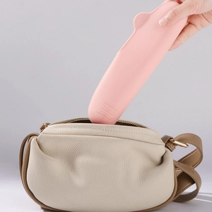 Pink silicone makeup brush holder being placed into a bag to show portable travel size