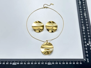 Detail view of irregular wavy gold-plated stainless steel round pendant and earring set