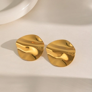 Close-up of shiny gold irregular wave earrings with reflective metallic finish and minimalist design