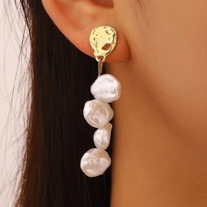 Detailed close-up of long drop earrings with four baroque pearls and textured gold studs