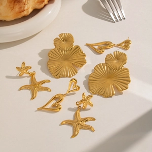 Elegant gold ginkgo leaf and starfish stainless steel earrings on a beige background