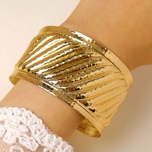 Detail of wide gold cuff bracelet featuring hammered texture and vintage stripes