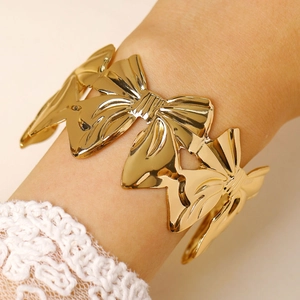 Detailed view of wide gold bow cuff bracelet with polished finish on model wrist