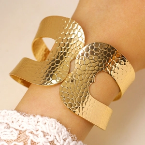 Close-up of golden wide open cuff bracelet with irregular hammered texture and cut-out detail