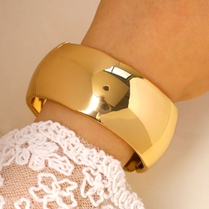 Close-up of minimalist gold wide cuff bracelet with mirror finish on model with lace sleeve