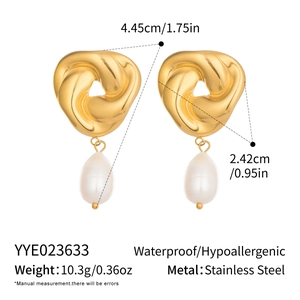 Détail de boucles d'oreilles en acier avec nœud doré et perle goutte blanche