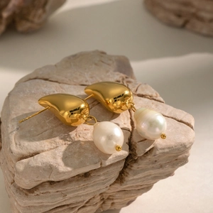Détail de boucles d'oreilles en perles avec accents dorés sur pierre naturelle
