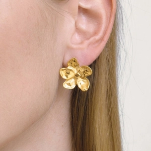 Vintage gold flower stud earrings with hammered metal texture worn by a model