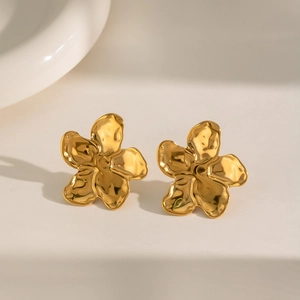 Detailed view of gold flower earrings with hammered texture and liquid metal finish