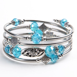 Detail of blue crystal beads and silver floral charms on a layered wrap bracelet