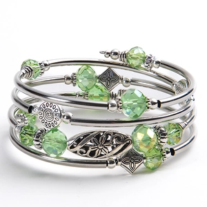 Detail of bohemian layered wrap bracelet with emerald green crystals and floral charms