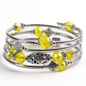 Detail of multi-layered stone bracelet with yellow crystal beads and floral metal charms