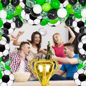 Detail of football theme party decorations with golden champion trophy and latex balloons