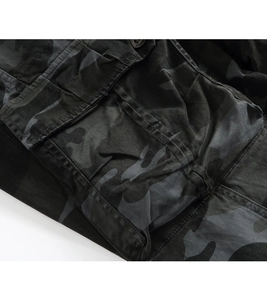 Detail of dark camo cargo pants showing the large flap pocket with design button and stitching