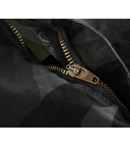 Close-up of vintage brass zipper on camouflage cargo pants with durable twill fabric