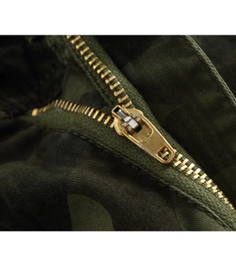 Close-up of golden metal zipper and durable jungle camouflage fabric on cargo pants