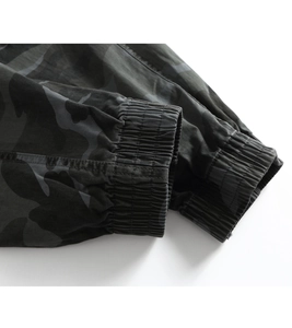 Close-up of elastic ribbed cuff on dark camo cargo pants with detailed stitching work