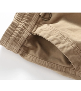 Detailed close-up of khaki cargo pants featuring elastic waist and metal D-ring buckle