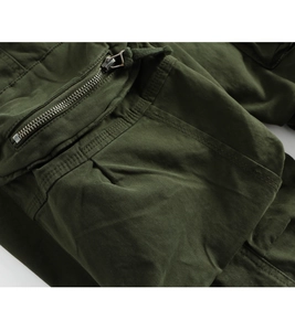 Detail view of army green cargo pants featuring a silver metal zipper and woven drawstring