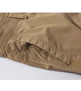 Detailed macro view of khaki cotton twill pants featuring belt loops and side pocket stitching