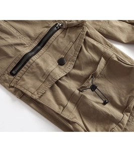 Detailed macro view of dark khaki cargo pants with metal zippers and snap button pockets