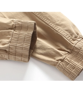 Detailed close-up of khaki cargo pants featuring elastic ankle cuffs and reinforced stitching