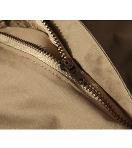 Detailed close-up of the vintage copper metal zipper on khaki twill cargo trousers