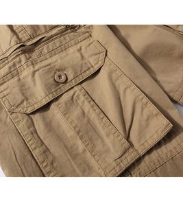 Macro shot of khaki cargo pants featuring buttoned flap pockets and reinforced stitching