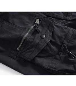 Detail of durable cargo pants showing metal zipper pocket and heavy-duty snap flap