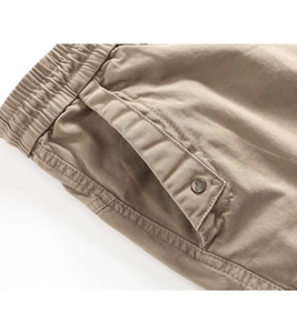 Detail of khaki cargo pants featuring elastic waist and vintage NK 1950 engraved button