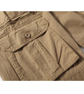 Close-up of khaki cargo pants pocket with reinforced stitching and resin button details