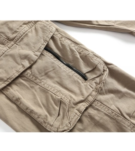 Detail of khaki cargo pants featuring large utility pocket and black zipper closure