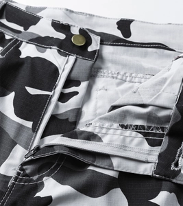 Detailed close-up of ripstop camo cargo shorts with brass button and metal zipper fly