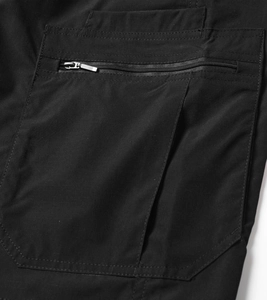 Detail of durable black cargo shorts fabric showing metal zipper and multi-layer stitched pocket