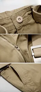 Detail of khaki cargo shorts showing waist button, zipper fly, and canvas belt buckle