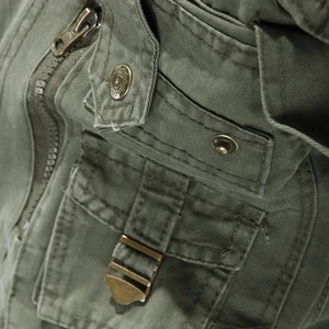 Army green cargo jacket detail featuring metal zipper and embossed star pattern buttons
