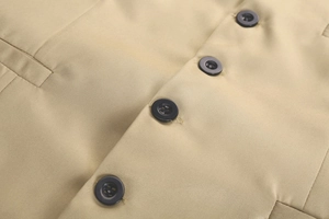 Close-up of khaki vest showing twill texture, black buttons, and detailed pocket stitching