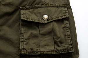 Detail of cargo short pocket featuring a vintage metal button and olive cotton fabric